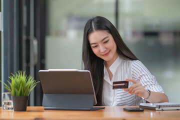 Young woman holding credit card and using a laptop computer. Online shopping concept	