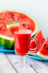 Delicious healthy refreshing low calories summer drink: watermelon smoothie or juice. Concept of seasonal desserts, detox, dieting. White wooden background, close up, macro
