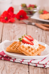 Waffles with strawberries and whipped cream.