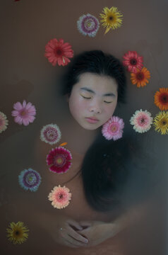 classic portrait of a girl like ophelia dreaming in water with colorful floating  flowers