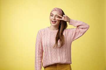 Cheerful happy glamour young european woman in pink knitted sweater, wearing headband, winking...