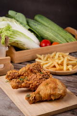 fried chicken with french fries on a wooden chopping board