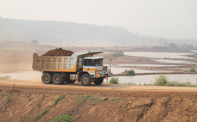 Closeup of dump-truck running on temporary road at dam construction site.