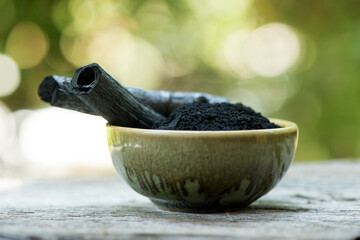 Bamboo charcoal ,green leaves and powder isolated on nature background.