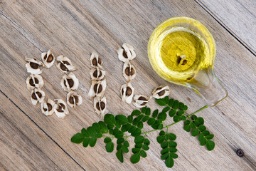 Moringa green leaves ,seeds and oil on an old wooden background.top view,flat lay..