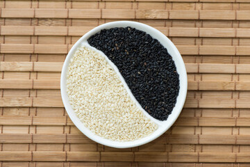 Black and white sesame seeds on bamboo background.