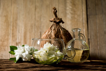 Cape jasmine flowers and extracts with coconut oil on an old wood background.