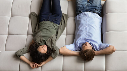 Above top view happy positive young family couple relaxing on comfortable sofa, enjoying peaceful...