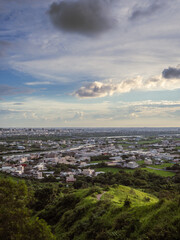 View of city from the beautiful mountain. Blue sky and green meadow in sunset time.