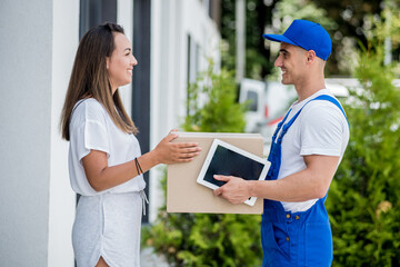 Young courier delivering goods to a young woman at home