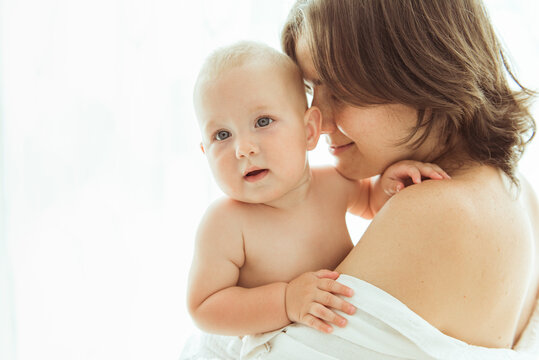 Mother kissing cute baby, child resting on mom shoulder, copy space. Family, child and parenthood concept