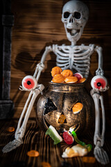 Ein Gerippe zu Halloween, welches einen Kürbis und Süßigkeiten dabei hat und gruselig ist