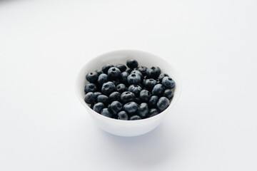 Beautiful ripe blueberries in a glass bowl on a white background. Healthy food, and vitamins.