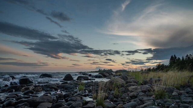 4K time lapse of Magnificent Soft and colorful sunset by the seaside stone. Beautiful cloud movement with seashore stones. Gradual light reduction.
