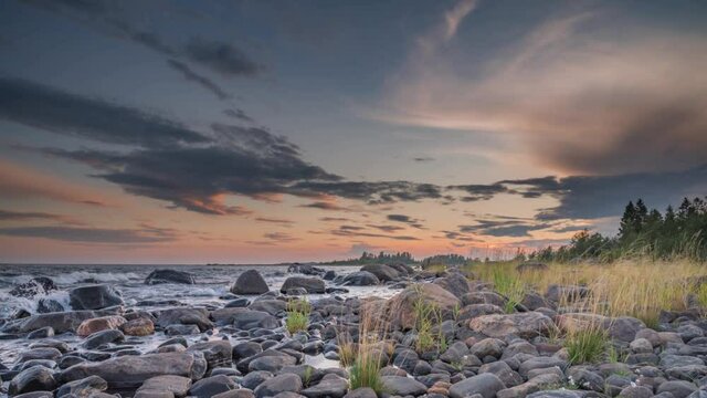 4K time lapse of Magnificent Soft and colorful sunset by the seaside stone. Beautiful cloud movement with seashore stones. Gradual light reduction.