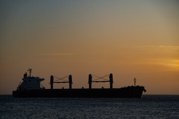 Obraz premium Silhouette of Cargo Container Ship at Sea during sunset. Concept of logistics and transportation 