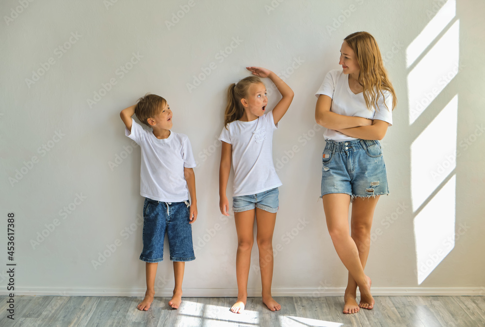 Wall mural concept of the family. mother measures growth of kids