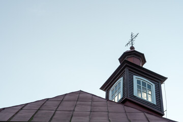 An old metal cross on the dome of a Christian church. An old wooden church. Celebration of Christian holidays baptism and communion in the church.