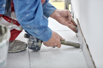 Ceramics tile man worker placing new tiles on the floor and wall.