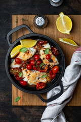 codfish with tomato sauce in a iron pan