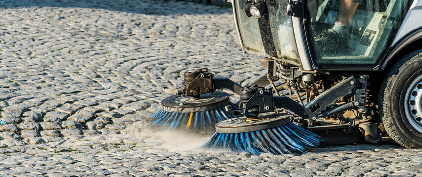A road sweeping machine on a cobblestone street