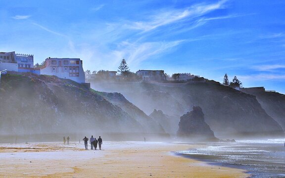 A family walking through sea fog on the beach at the Mirleft, Morocco
