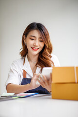 Naklejka premium Portrait of Starting small businesses SME owners female entrepreneurs working on receipt box and check online orders to prepare to pack the boxes, sell to customers, sme business ideas online.