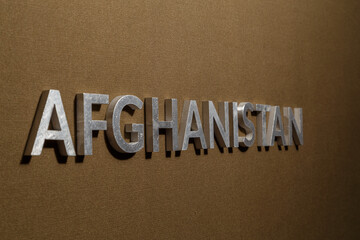 the word afghanistan laid with silver metal letters on rough tan khaki canvas fabric