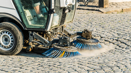 A road sweeping machine on a cobblestone street