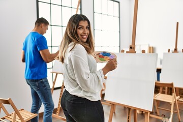 Two students smiling happy painting at art school.