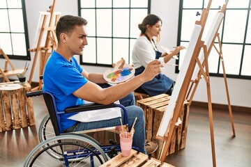 Two students smiling happy painting at art school.