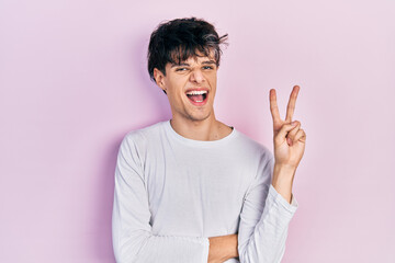 Handsome hipster young man wearing casual white shirt smiling with happy face winking at the camera...