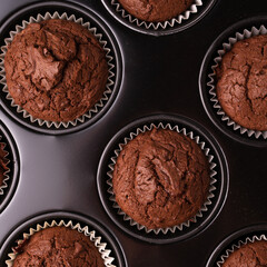 Fresh baked homemade raisin bran muffins in baking dish on dark gray texture background. Close up, copy space, horizontal view from above