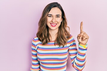 Young hispanic girl wearing casual clothes showing and pointing up with finger number one while smiling confident and happy.