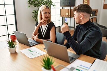 Two business workers speaking and working at the office.