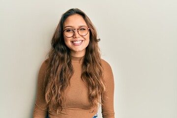 Young hispanic girl wearing casual clothes and glasses with a happy and cool smile on face. lucky...