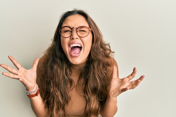 Young hispanic girl wearing casual clothes and glasses celebrating mad and crazy for success with...