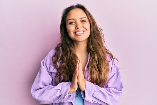Young hispanic girl wearing casual clothes praying with hands together asking for forgiveness smiling confident.