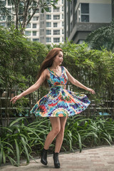 Beauty young asian woman in casual colourful dress spinning in the park. Long hair. summer day....