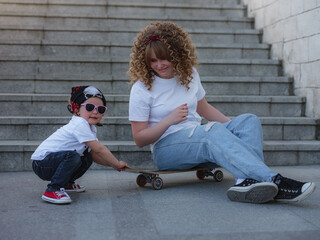 The older sister spends time with the younger sister. A walk in the city with a skateboard. - 453623731