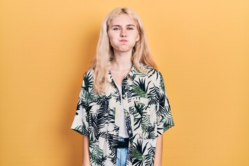 Beautiful caucasian woman with blond hair wearing tropical shirt puffing cheeks with funny face....