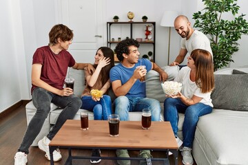 Group of young friends having party sitting on the sofa at home.