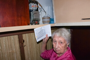 Terrified woman is checking electricity meter - consumption and expensive electricity concept