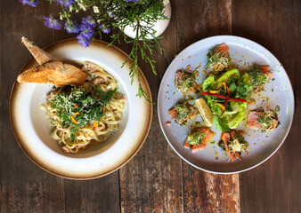 Salmon tataki and salmon pasta. Fancy dinner close-up. Slices of sashimi grade red fish seared lightly to keep the fish raw inside. Japanese and Italian cuisine. Gourmet fine dining restaurants.