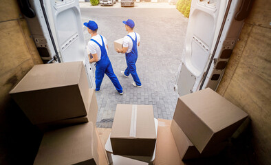 Two removal company workers unloading boxes from minibus