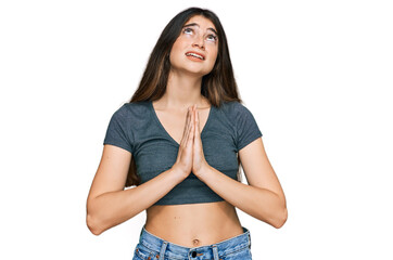 Young beautiful teen girl wearing casual crop top t shirt begging and praying with hands together...