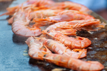 Street food festival, chef cooking delicious shrimps on a spit.