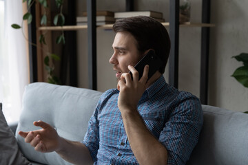 Serious thoughtful mobile phone user making telephone call from home, speaking on cell....
