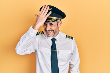 Handsome middle age man with grey hair wearing airplane pilot uniform surprised with hand on head for mistake, remember error. forgot, bad memory concept. © Krakenimages.com