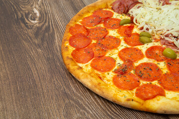Pizza half peperoni, with space for text. On a wooden table.